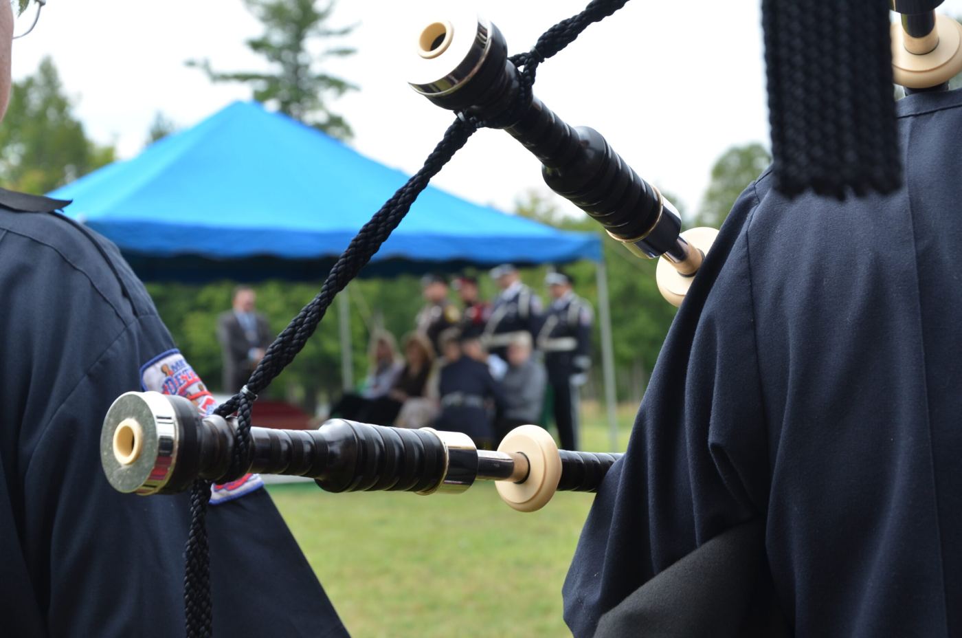 Close view of bagpipe drones on a member's shoulder at a graveside service