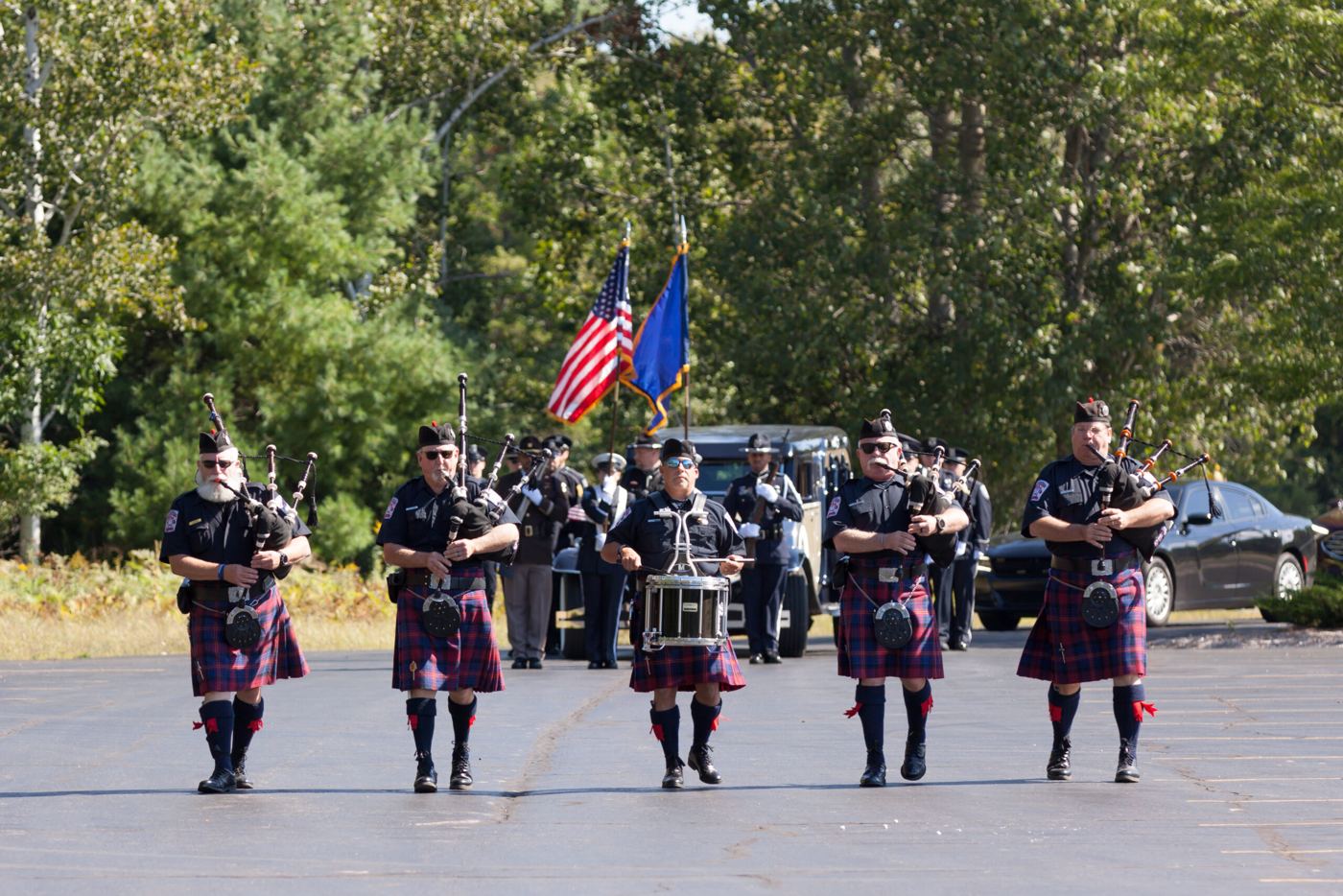 Pipers and a drummer march ahead of the U.S. and Michigan flags